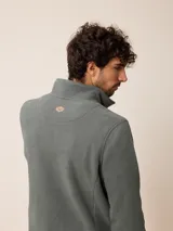 Sweater de polar color beige, con cuello alto y cierre frontal parcial. Presenta un pequeño logo bordado en el pecho.