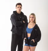 Campera con cierre frontal metálico, confeccionada en algodón pesado de alto gramaje. Presenta un diseño oversize con capucha, bolsillos tipo canguro y bordados minimalistas en el frente y en la manga.