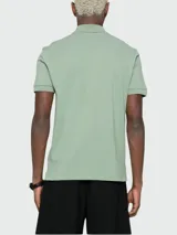 Polo de manga corta color verde menta, confeccionado en piqué de algodón, con cuello y tapeta de tres botones. Presenta un logo bordado tono sobre tono en el pecho.