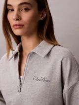 Buzo gris melange de french terry, con cuello tipo polo de media cremallera y manga larga. Presenta el logo de Calvin Klein bordado en el pecho.