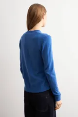 Cardigan de punto azul con cuello redondo, manga larga y cierre frontal abotonado con pequeños botones al tono.
