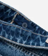 Pantalón de jean azul de corte barrel, con pences delanteros, cintura con trabillas, cierre tradicional y terminación deshilachada.