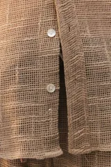 Camisa amplia y relajada de algodón liviano color blanco, de trama abierta y textura, con cuello camisero, mangas cortas y cierre de botones al frente.