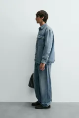 Sobrecamisa de denim de algodón con efecto lavado, corte regular fit, cuello solapa, cierre frontal de botones, manga larga con puños abotonados y dos bolsillos frontales con solapa en el pecho.
