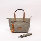 Bandolera verde militar con diseño acolchado y pespuntes diagonales, doble asa de mano en tono tostado y correa ajustable y desmontable. Cuenta con cierre superior y un bolsillo frontal con cremallera decorado con un llavero de cordón naranja con cuentas.