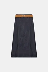 Falda midi de denim azul oscuro con costuras a la vista en contraste. Presenta un diseño de corte recto con paneles verticales y un cinturón de gamuza en tono tostado con hebilla metálica.