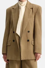 Blazer amplio de silueta cruzada, color camel/tostado, con solapas y cierre frontal de doble botonadura con botones oscuros. Presenta bolsillos con solapa.