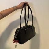 Bolso tipo baguette negro de cuero sintético con doble asa corta y cierre superior con cremallera.