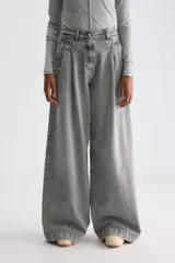 Jean de denim rígido gris con lavado acid wash, tiro medio y calce amplio de perneras extra anchas. Cuenta con pinzas en la parte delantera y cierre frontal con cremallera.