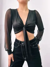 Top negro de microfibra con escote en V, mangas largas de tul y nudo frontal.