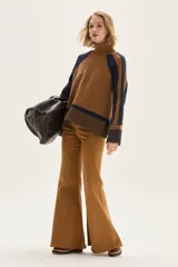 Polera de cuello alto confeccionada en lana lambswool, con diseño de bloques de color en tonos beige y marrón. Presenta mangas raglán con textura acanalada y detalles en hilo metalizado lurex.