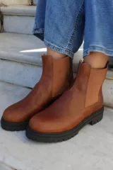 Bota tipo chelsea de cuero color chocolate, con paneles laterales elásticos y suela track de goma negra.