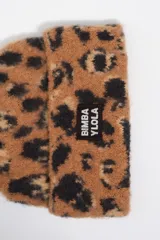 Gorro tipo beanie de punto con estampado animal print de leopardo en tonos beige y gris. Presenta un parche rectangular con el logo de la marca en la parte frontal.
