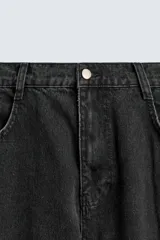 Pantalón cargo de denim lavado negro, corte relajado y tiro medio. Presenta múltiples bolsillos cargo con solapa y detalle de cierre en las perneras, además de bolsillos de vivo traseros. El bajo es ajustable con trabilla.