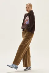 Pantalón de pana de corte recto y pierna ancha, color camel, con bolsillos frontales y costuras verticales decorativas en el frente.