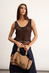 Musculosa de punto color blanco crudo, con escote en V y terminaciones con bordado artesanal amarillo.