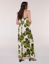 Vestido maxi de fondo blanco con estampado de flores grandes en tonos verde y marrón, con escote en V, breteles finos y detalle de abertura cut-out en el centro del busto.