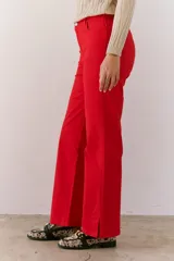 Pantalón color beige de corte recto, confeccionado en algodón y spandex. Presenta tiro medio y cierre frontal con botón y cremallera. Incluye cinturón marrón con hebilla plateada.