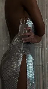 Vestido corto de malla metálica plateada, con escote drapeado, espalda descubierta con tiras cruzadas y tajo lateral en la falda.