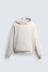 Sudadera tipo hoodie de color blanco hueso, con capucha, manga larga y bolsillo canguro frontal. Presenta un calce relajado y tejido de algodón con interior afelpado.
