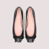 Bailarinas negras de cuero capitoneado con puntera de charol y moño decorativo. Interior de cuero color rosa y suela de goma antideslizante.