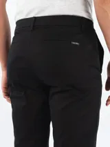 Pantalón de hombre color negro, corte slim, con cierre de botón y cremallera.