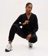 Campera deportiva de mujer confeccionada en tejido plush aterciopelado, con cuello alto, cierre frontal con cremallera y puños ajustados.