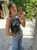 Top corto negro con lentejuelas plateadas y tirantes anchos color rosa.