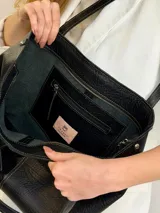 Cartera tote de cuero con pelo vacuno en tonos blanco y negro, con asas largas de hombro, parche frontal con logo y charms colgantes en forma de estrella y mini monedero.