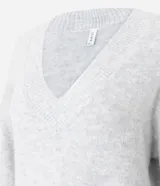 Suéter de punto color gris con escote en V y mangas largas. Presenta un diseño alargado con un detalle de encaje blanco en el ruedo inferior.