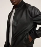 Campera estilo bomber de hombre, color marrón oscuro, confeccionada en poliuretano (PU) con cuello alto, cierre frontal y puños y bajo acanalados.