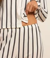 Conjunto de pijama largo de dos piezas: camisa de manga larga con cuello de pico y cierre delantero de botones, y pantalón con cintura elástica y puños ajustados. Estampado con rayas verticales.
