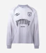 Remera de manga larga estilo deportivo con corte boxy, confeccionada en poliéster. Presenta cuello redondo, paneles laterales en tejido texturizado y estampados gráficos estilo tribal y lettering gótico en el frente.