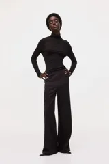 Pantalón de punto pesado color negro, de corte recto y acabado cepillado suave, con elástico revestido en la cintura y bolsillos parche delanteros con botón.