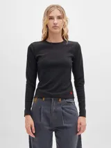 Camiseta de manga larga en tejido acanalado de color negro, con cuello redondo y costuras a contratono en color rojo. Presenta un corte ajustado al cuerpo y un pequeño logo bordado en color rojo en la parte inferior.