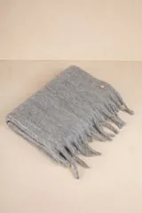 Bufanda rectangular color beige con flecos en los extremos.