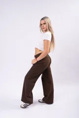 Pantalón de corte wide leg en color marrón, confeccionado en tejido con elastano. Presenta tiro medio, cierre frontal con botón y bolsillos laterales.