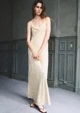 Vestido largo color crudo con sutil textura en relieve, escote drapeado y tirantes finos.