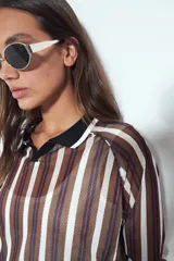 Remera de manga larga con tejido tipo mesh, diseño de rayas verticales en tonos marrones y blancos, cuello polo negro y puños tejidos con detalle de rayas.