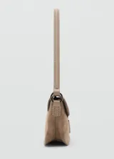 Bolso de hombro tipo baguette confeccionado en piel de serraje color tostado. Presenta un diseño rectangular con solapa frontal decorada con un detalle metálico y pespuntes visibles. Incluye un asa fija y forro interior.