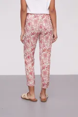 Pantalón de corte recto con estampado floral en tonos coral y verde sobre fondo crudo. Tiene bolsillos laterales y cintura elástica.