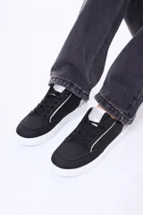 Championes urbanos de diseño minimalista en color negro, con detalles en plateado en la lengüeta y el talón. Presentan suela blanca de goma y cordones negros al tono.