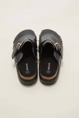 Suecos negros de estilo zueco con capellada de cuero sintético, detalle de hebilla metálica dorada y tachas decorativas alrededor de la suela. Poseen plantilla ergonómica y suela de plataforma dentada.