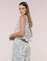 Blusa crop sin mangas de color blanco con estampado botánico de hojas verdes, cuello redondo y detalle de puntilla calada en el ruedo.