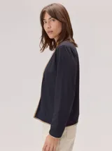 Remera de manga larga en color negro, con diseño de cuello redondo y terminaciones con vivos en contraste color beige. Presenta un corte recto y minimalista.