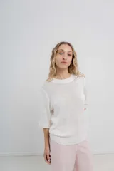 Buzo de tejido abierto color beige claro, de calce oversize con mangas 3/4 y cuello redondo. Presenta terminaciones acanaladas en puños y cintura.