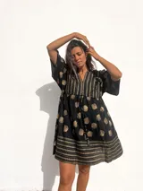 Vestido corto tipo túnica de color negro con estampado de hojas doradas y detalles geométricos.