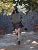 Buzo color crudo con cuello de piel sintética color crema, abertura parcial con cierre de cuero marrón y hebilla dorada, puños con ajuste de cuero marrón y bolsillos laterales.