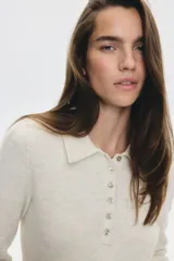 Buzo de punto suave con lana, de corte entallado, cuello camisero, tapeta con botones y terminaciones acanaladas en puños y bajo.