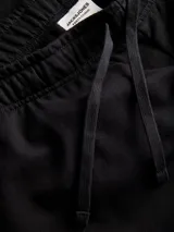 Short jogger de felpa color negro, con cintura elástica con cordón ajustable, costuras decorativas en contraste y el nombre de la marca estampado verticalmente en el lateral.